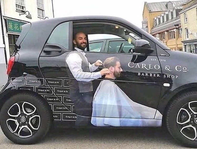 small car with a big graphic ad promoting barber shop