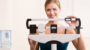 Woman weighing herself on scales in health club