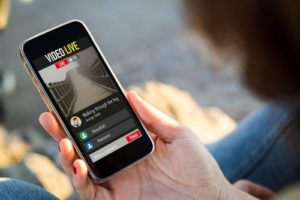 Person staring down at iPhone looking at Facebook live video