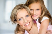 Mother and daughter posing happily on blue fuzzy background