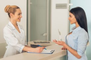 Female patient talking to female medical professional at front desk