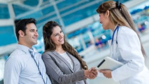 Doctor handshaking with a couple at the hospital