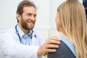 Doctor putting comforting hand on female patient's shoulder