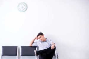 Man with an impatient expression sitting down in waiting room