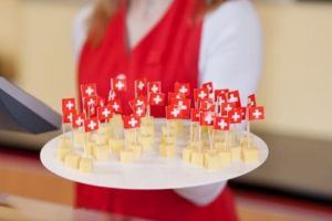 Woman holding up a sample tray of cheese with little medical toothpick flags sticking out