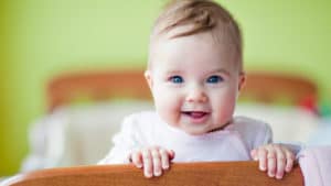 baby smiles standing in the crib