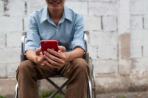 man in wheelchair checking mobile phone