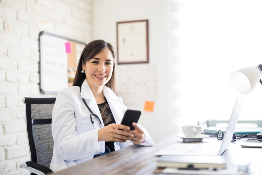 Doctor sitting at desk with cell phone in hand