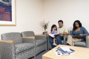 Family sitting down reading magazines in waiting room