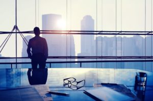 Silhouette of a man looking out an office window in conference room