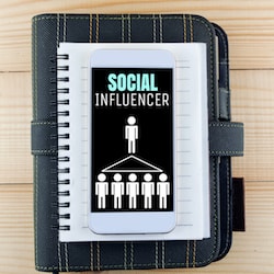 social influencer screen on smartphone on top of notebook and planner on wooden table