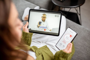 Woman video calling a doctor on her tablet and cell phone with medical testing data.