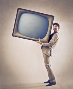 Tiny man holding up a huge tv