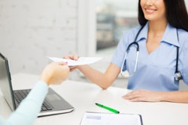 Female patient taking paper from female nurse sitting across from her