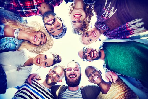 Young adults in a group circle looking down at the camera, all smiling