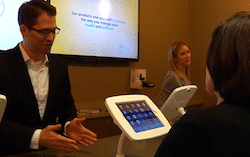 Screen Shot of a man talking to woman at a conference